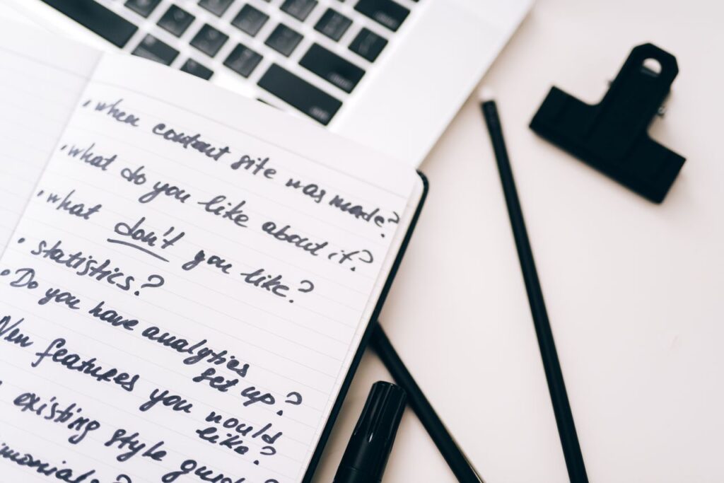 A close-up view of a notebook with handwritten notes alongside a laptop for planning and strategy.